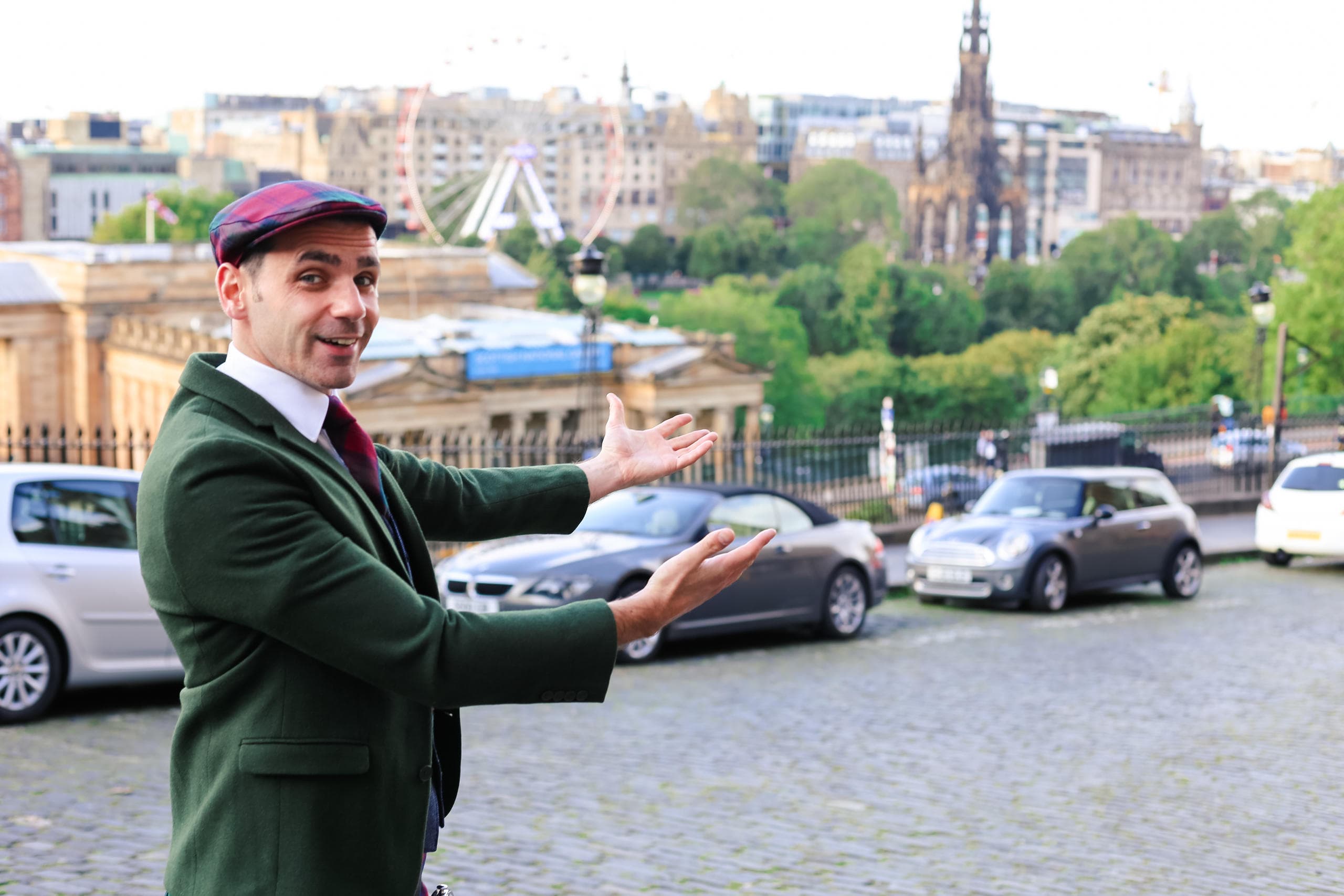 Tour guide gesturing toward Edinburgh skyline on cobbled terrace