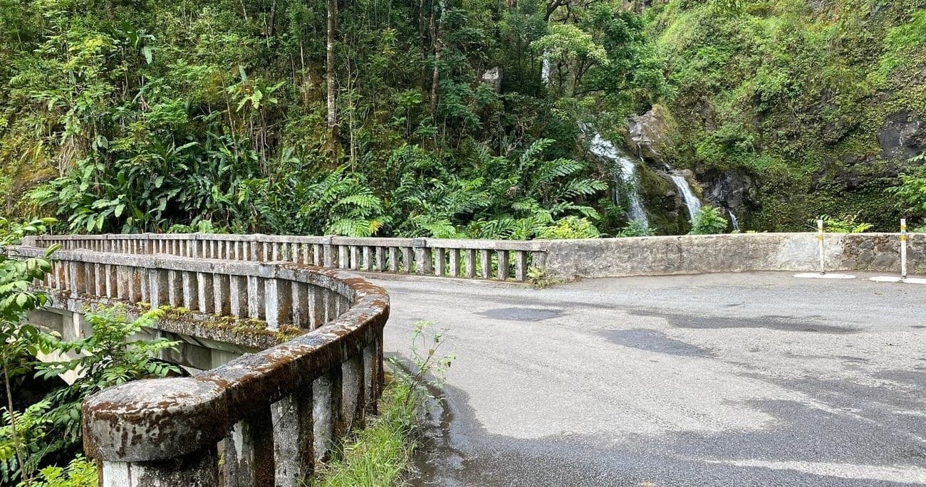 Winding mountain road through rainforest with waterfall vista