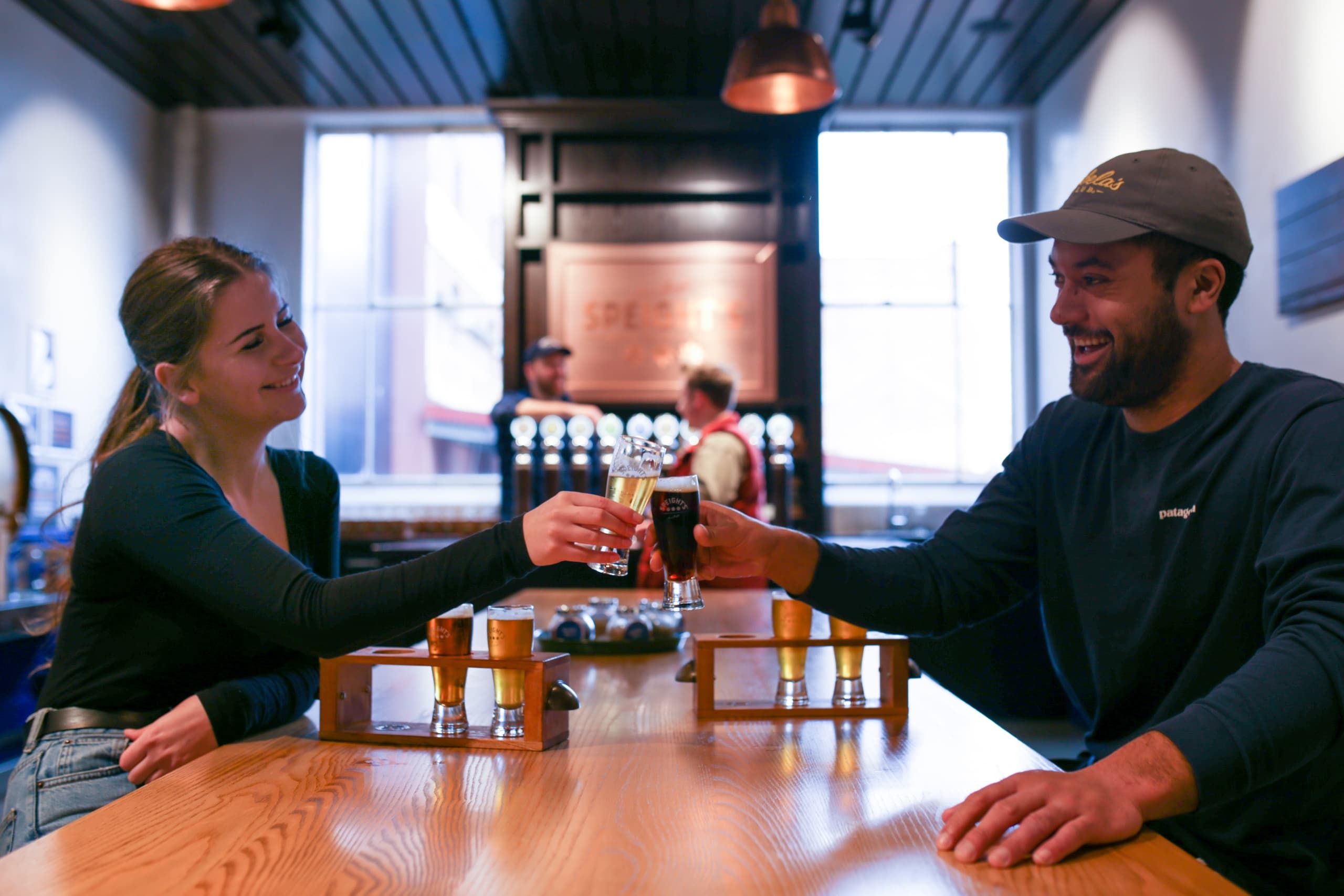 Friends clinking beer glasses in indoor brewery tasting room