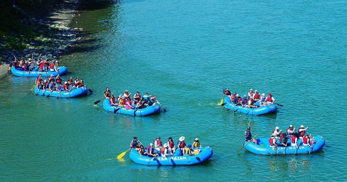 Aerial view of multiple rafts navigating turquoise river rapids