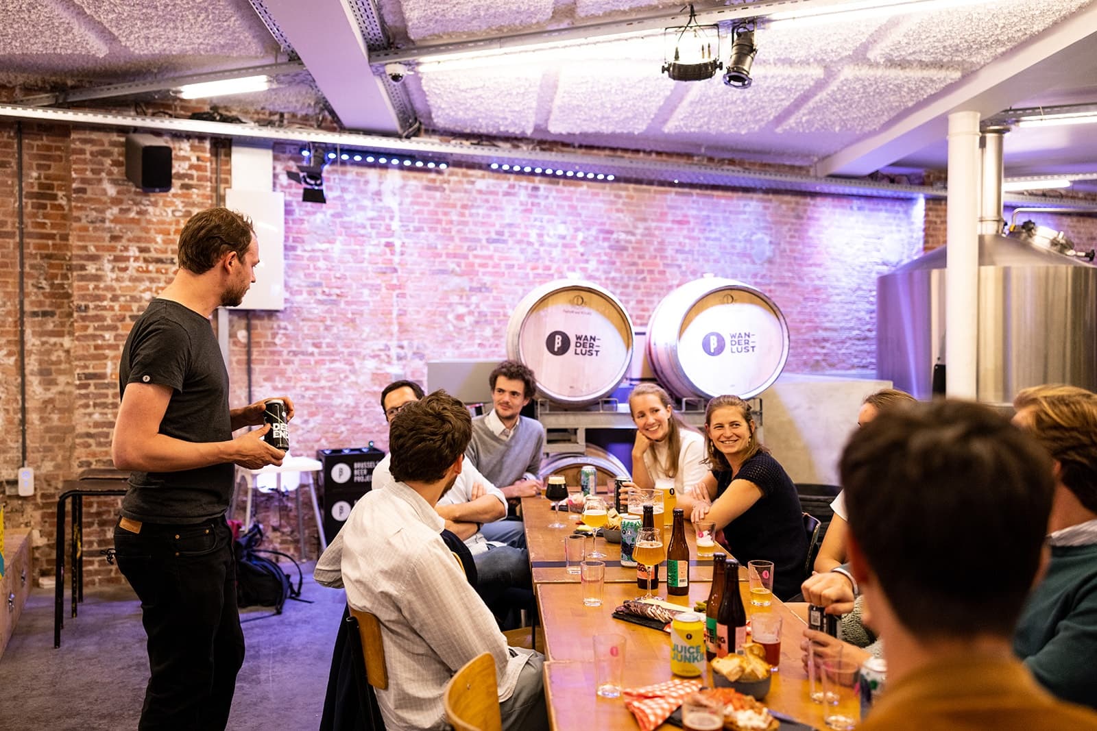 Guests enjoying communal beer tasting in brick-walled brewery