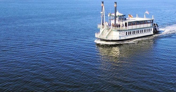 Riverboat cruising on calm open water under clear sky