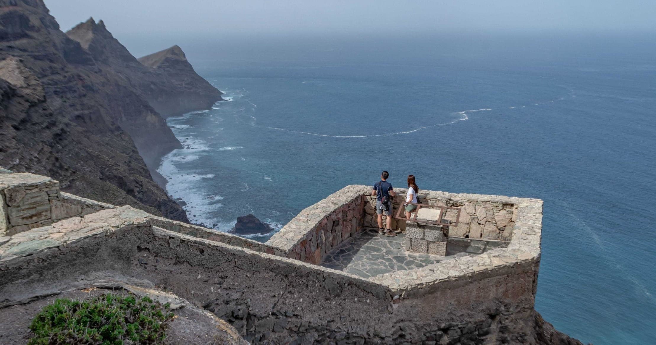 Scenic coastal lookout with travelers atop cliffs overlooking ocean