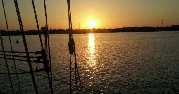Sunset view from sailboat cockpit with rigging and calm bay