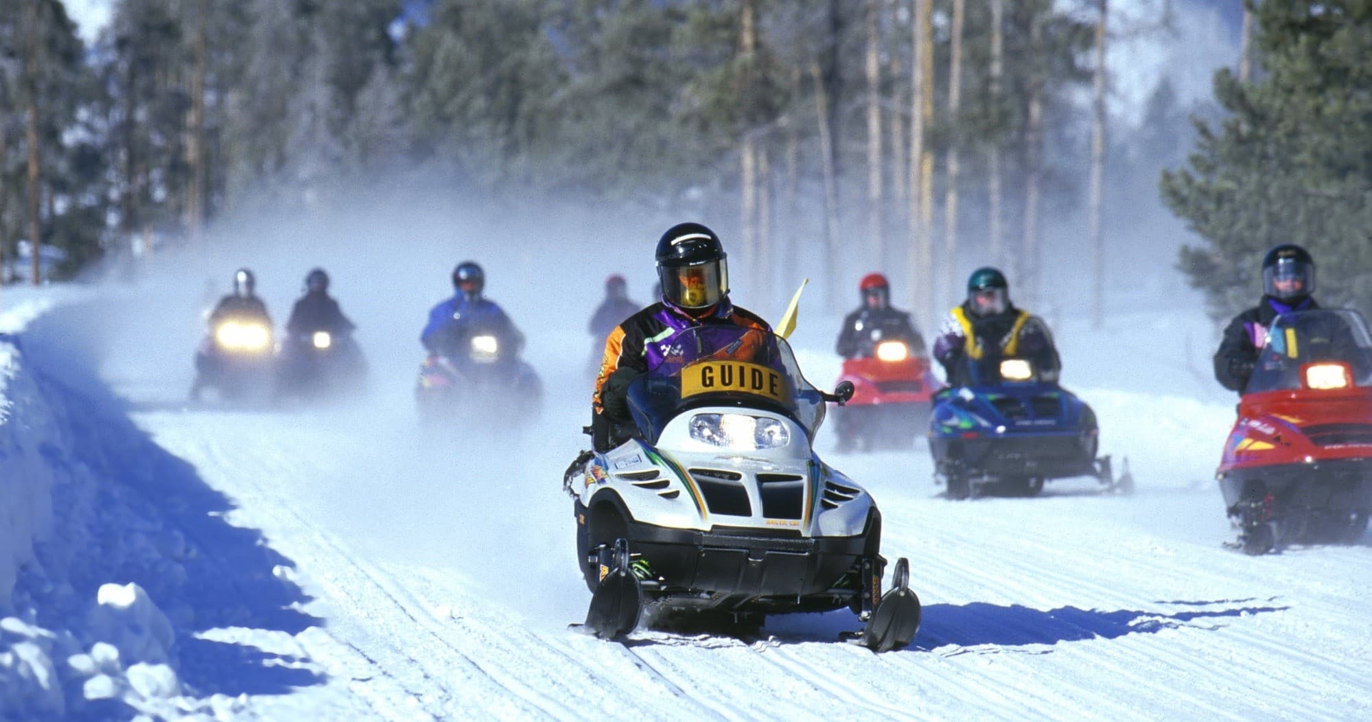Guided snowmobile tour on snowy forest trail, high-speed winter ride