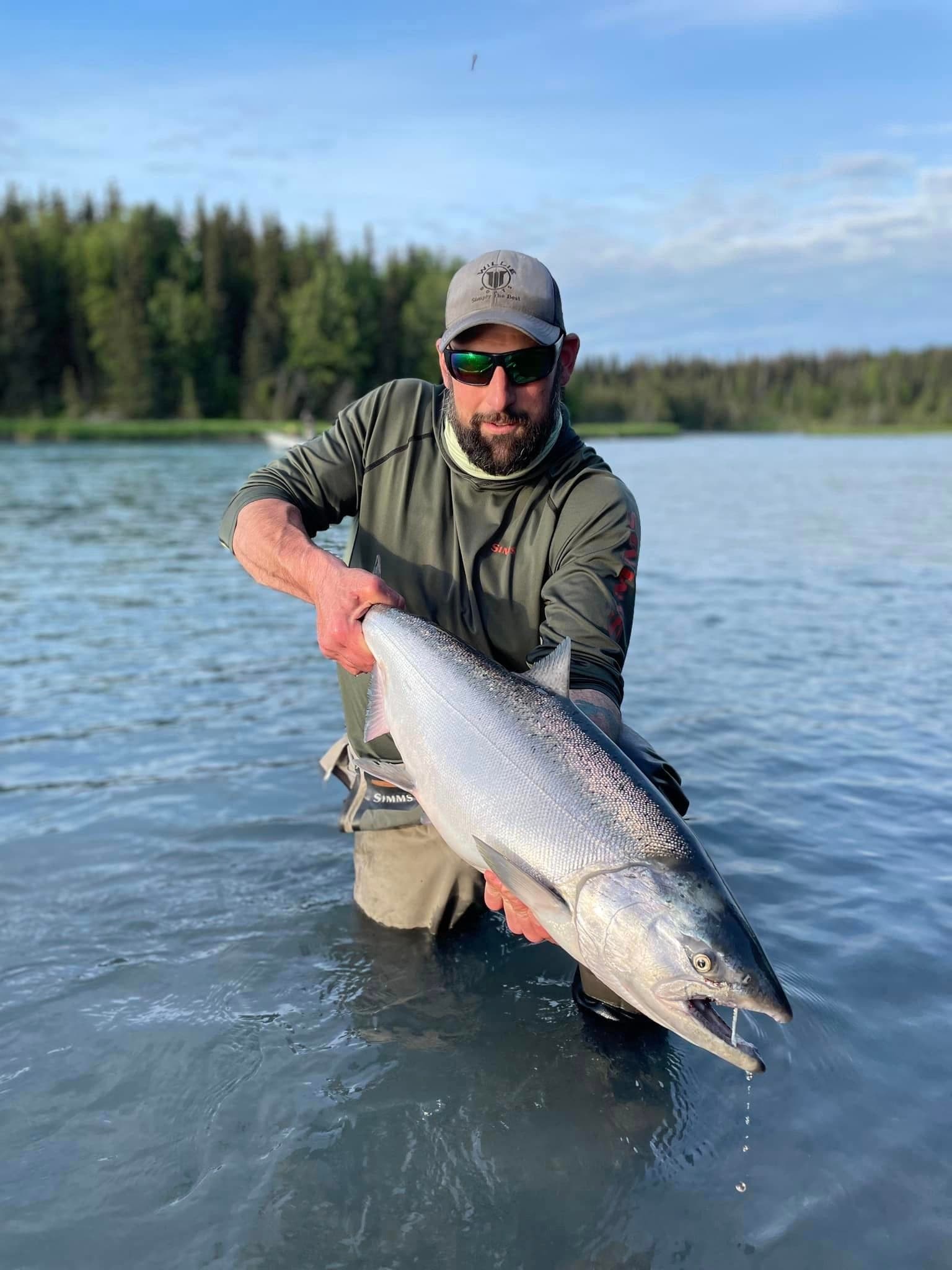 Fisherman knee-deep in river holding trophy salmon