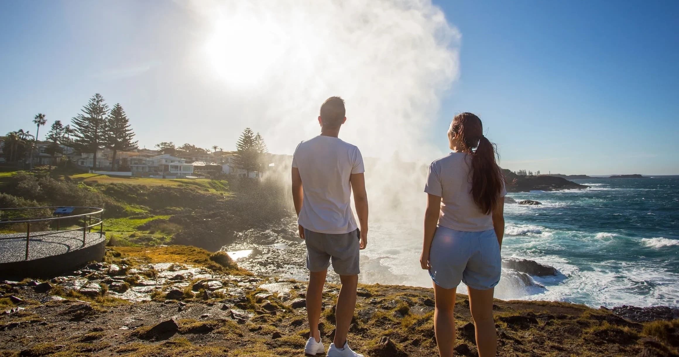 Couple hiking along rocky coastal cliffs with ocean spray