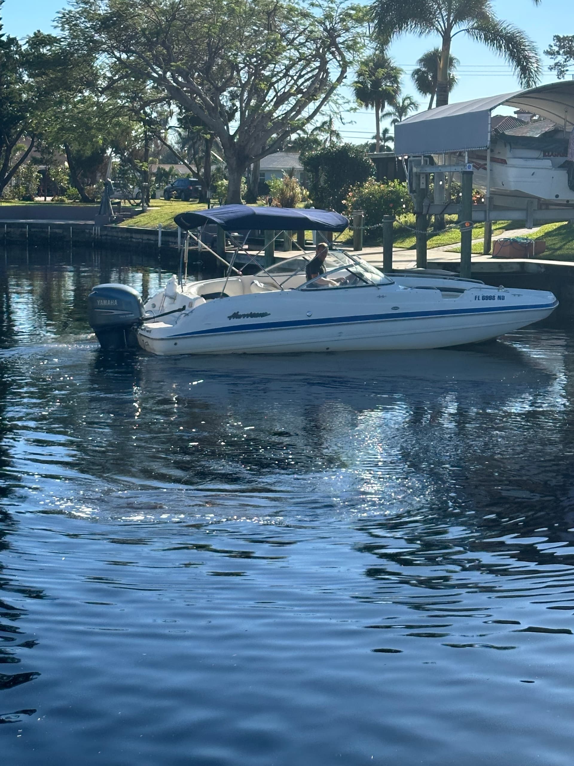 Bowrider motorboat docked in canal with waterfront homes reflected