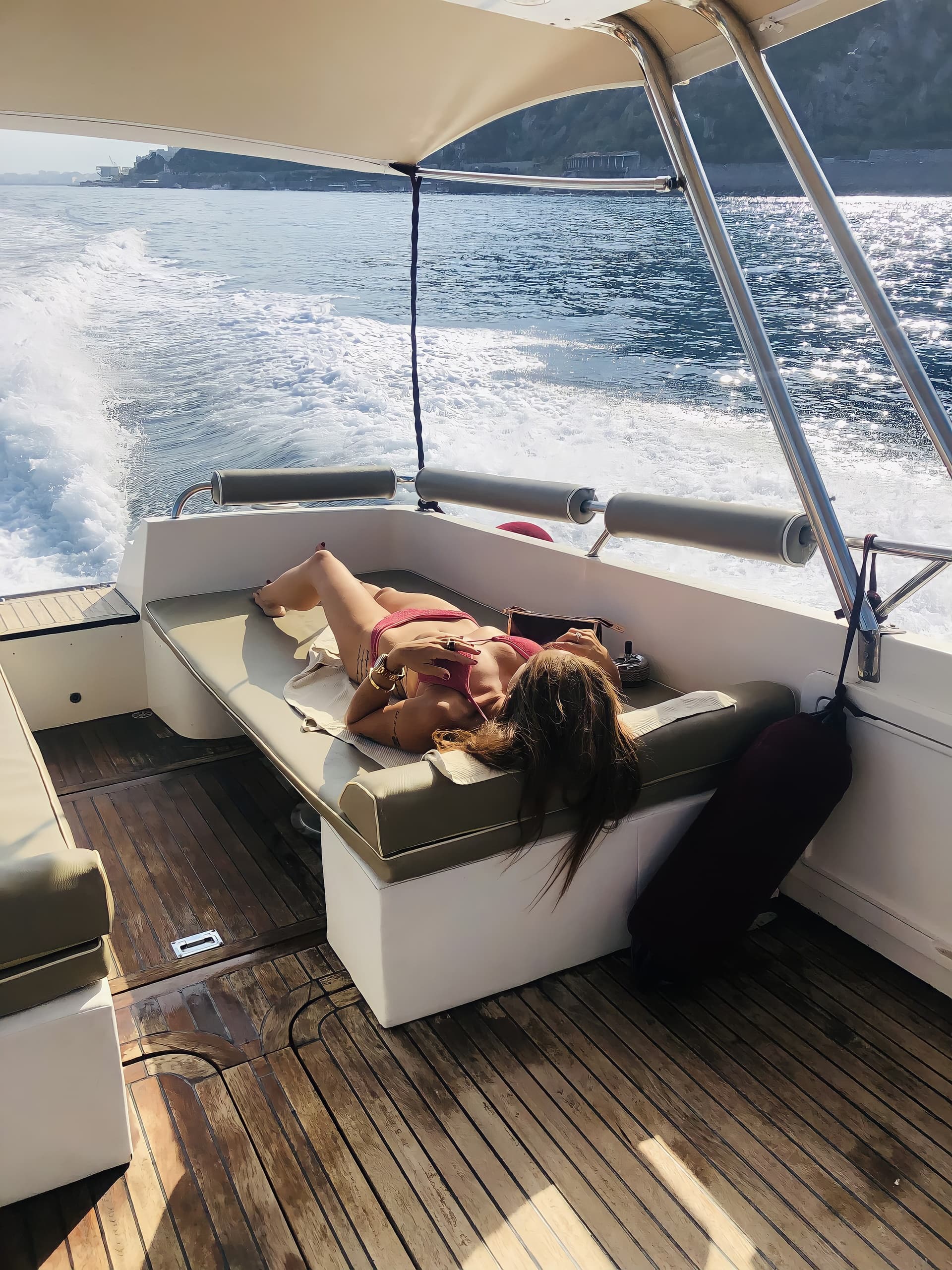 Relaxing aboard motorboat cruising coastal waters with sunbather