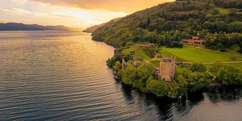 Castle ruin perched above loch with sweeping mountain backdrop