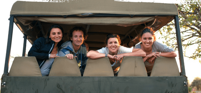 Tourists in open safari vehicle on African savanna game drive