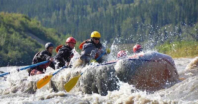 Group whitewater rafting plunging through churning river waves
