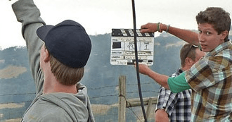 Film crew clapperboard on hillside filming tour location outdoors