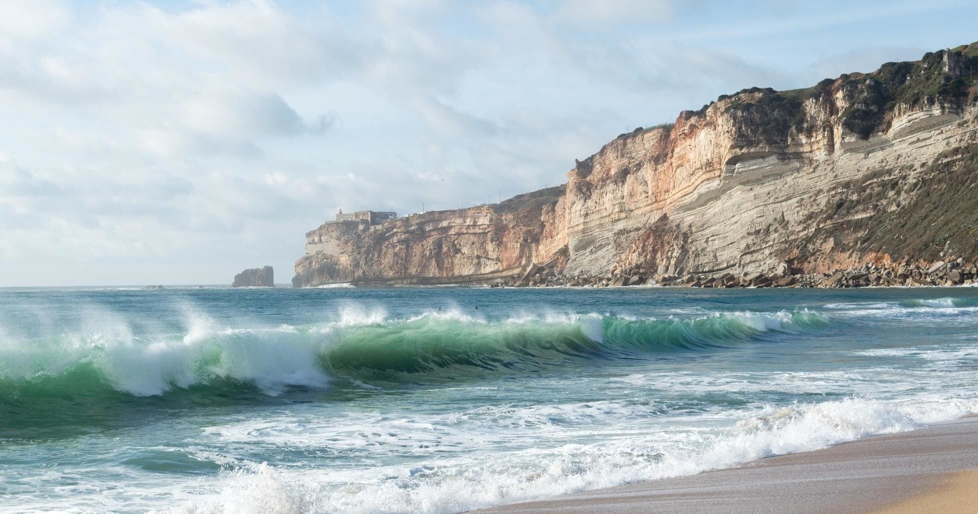 Waves crashing at rugged beach cliffs, surf coastal scenery