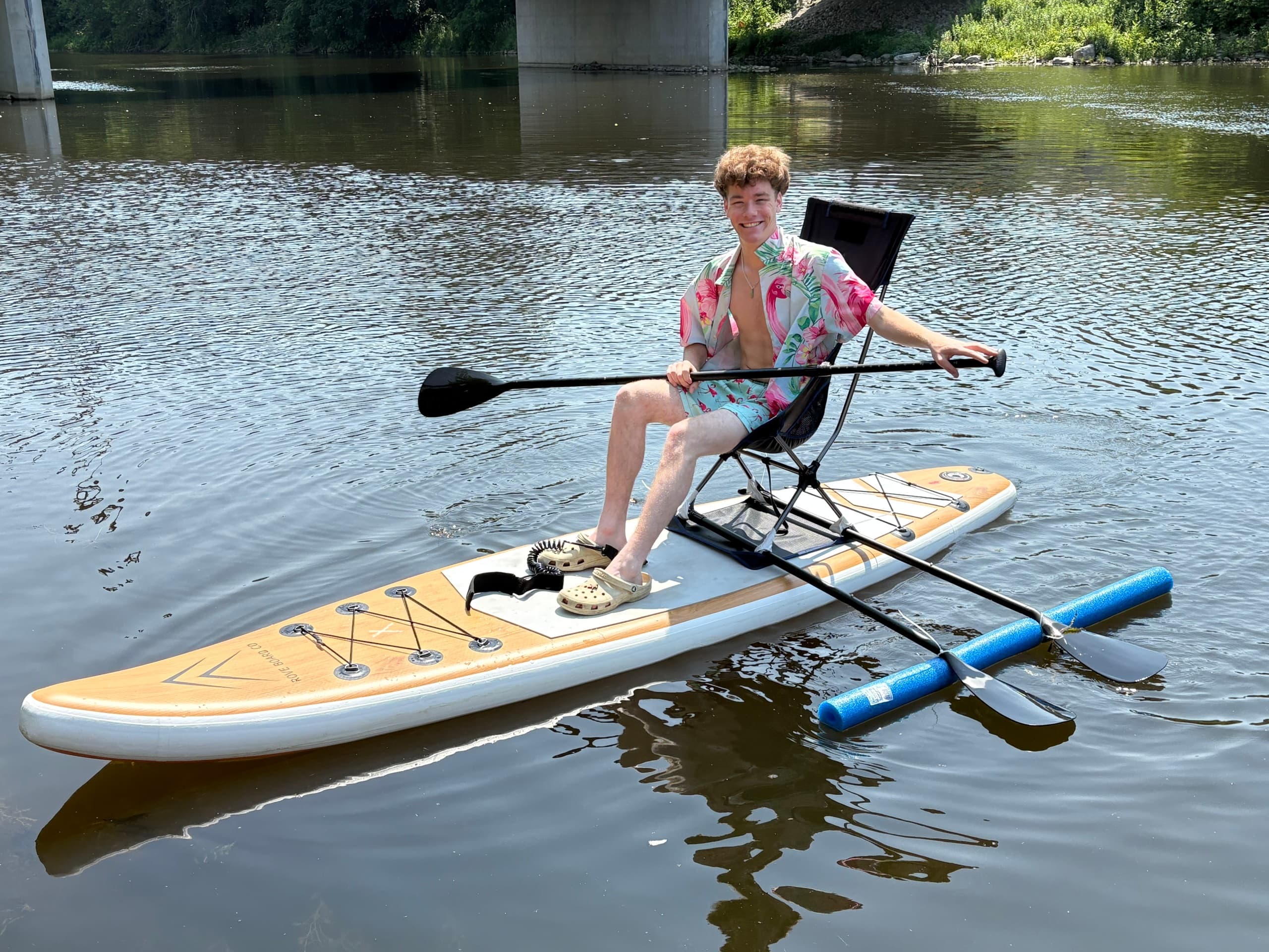 Person seated on paddleboard rowing across a tranquil river