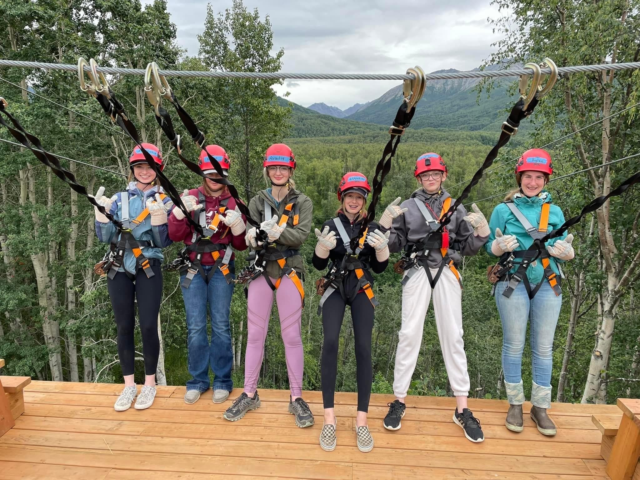 Group geared up on zipline platform among birch trees in Alaska