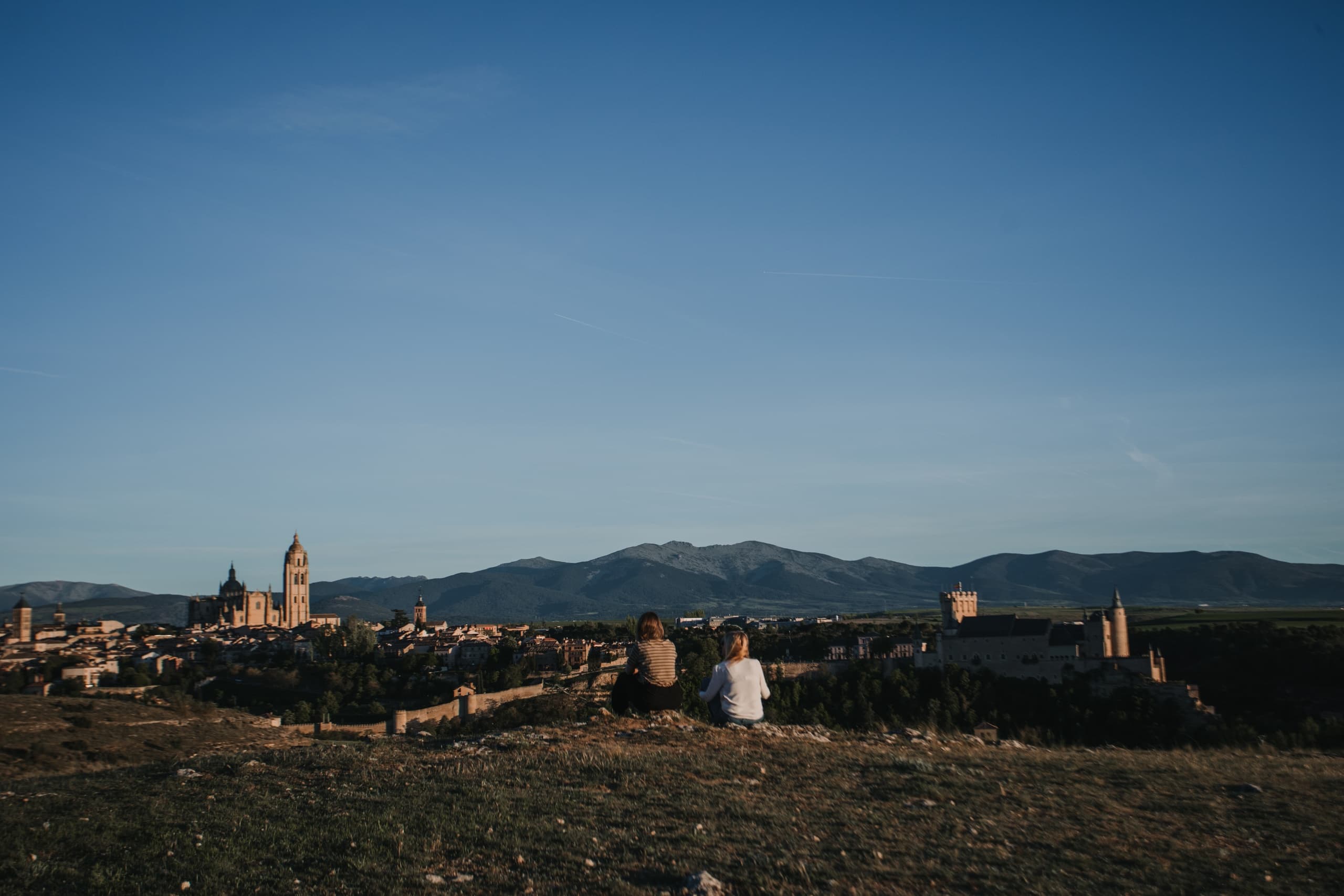 Couple overlooking historic town and distant mountains from hilltop