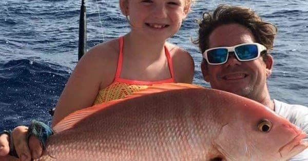 Father and daughter holding snapper on offshore fishing charter