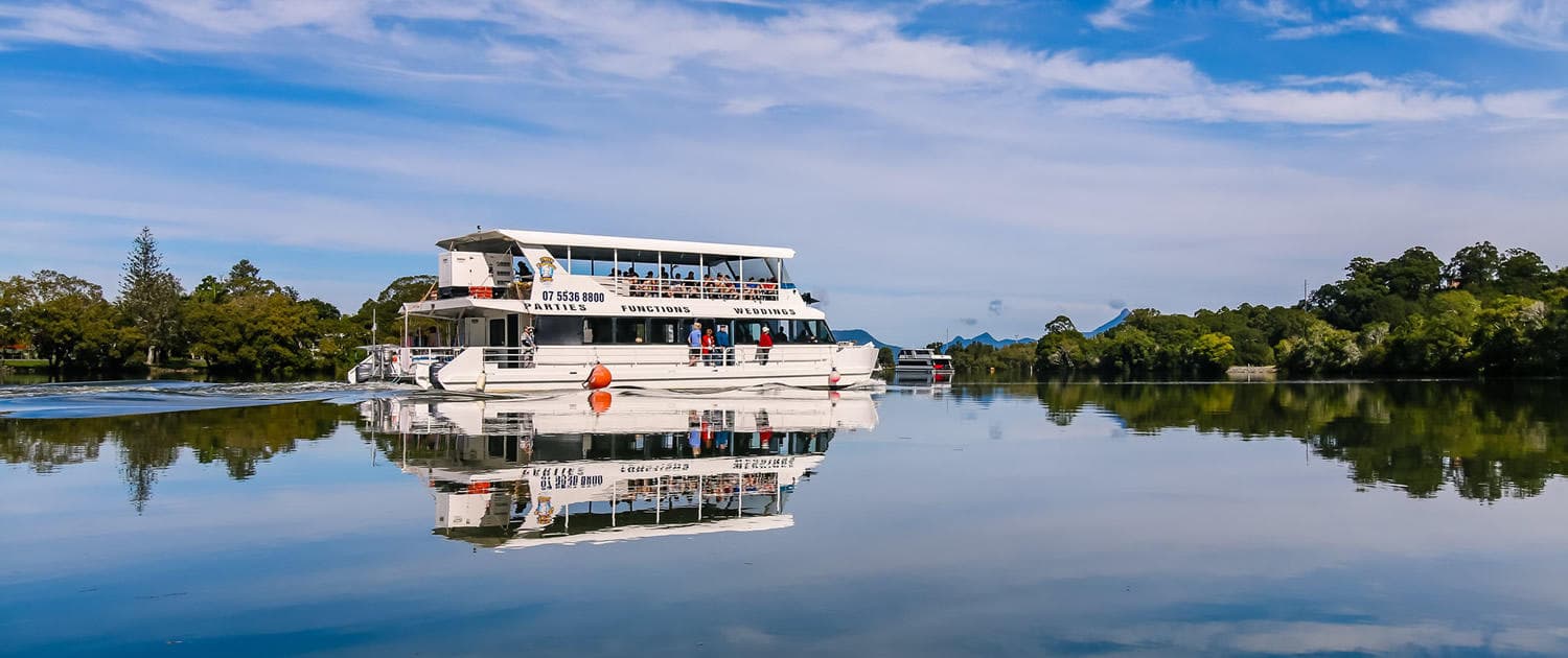 Scenic river cruise boat reflecting on calm river near wetlands
