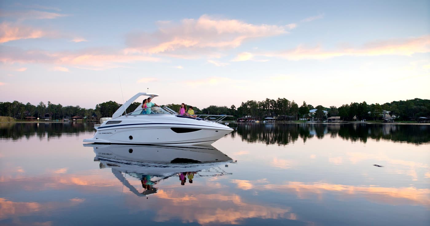 Luxury yacht cruising on calm reflective lake at sunset