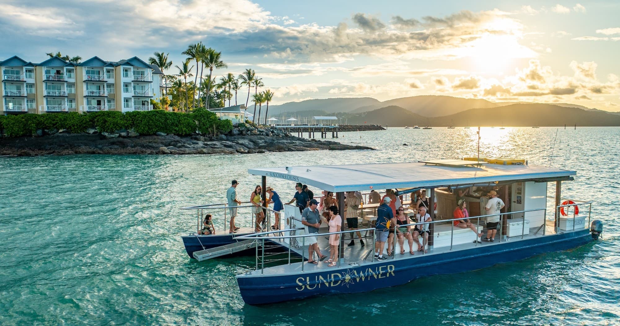 Island sightseeing tour boat at sunset in Whitsunday coastal waters