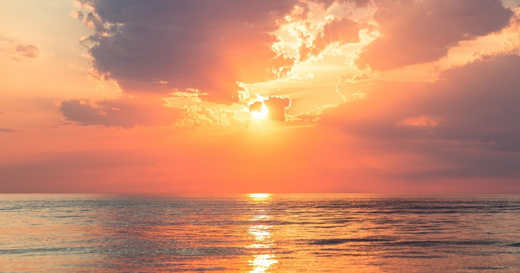 Sunset over calm ocean horizon, golden light boating scene