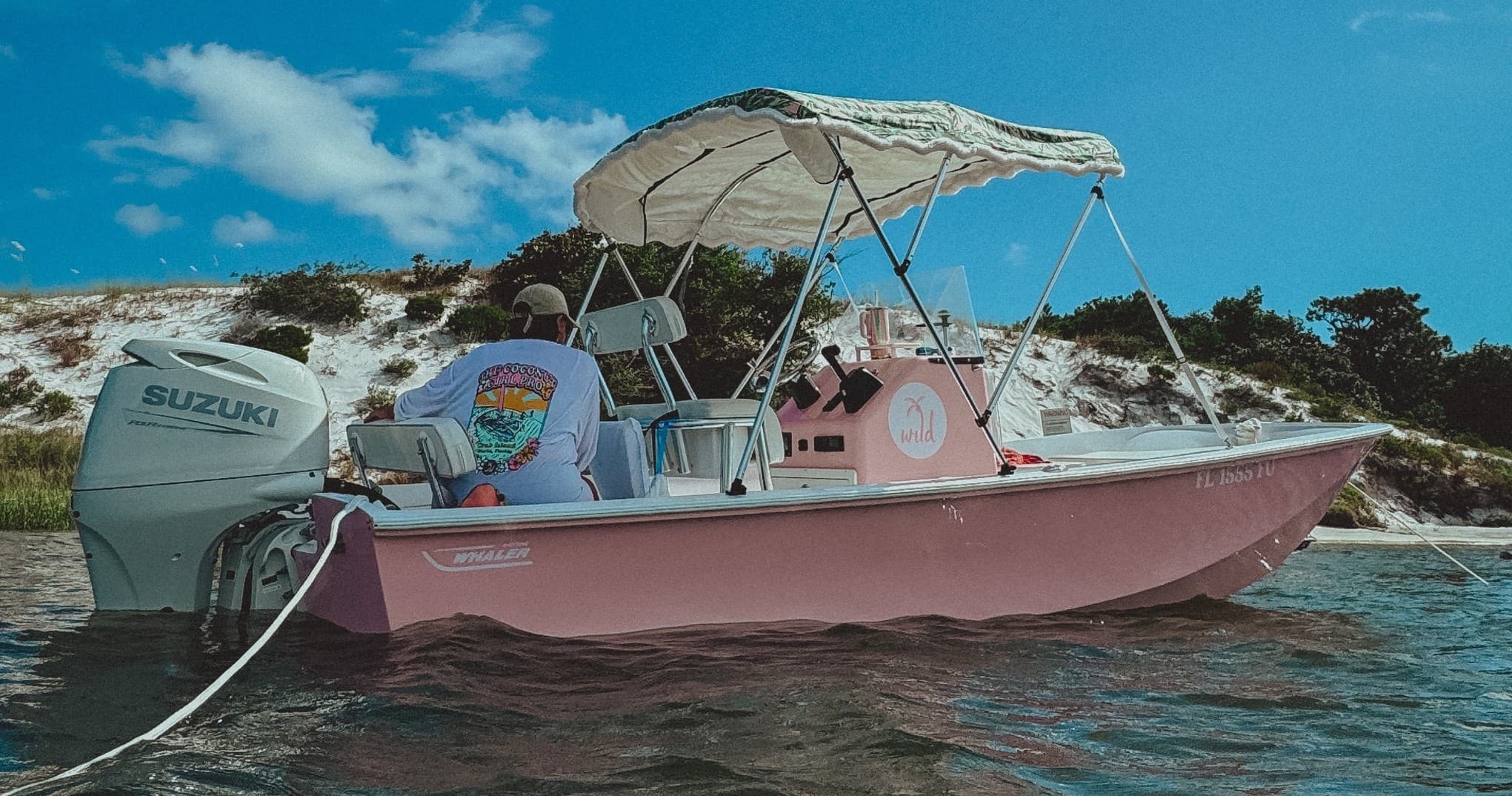 Pink skiff anchored near sandy shore, coastal boating outing