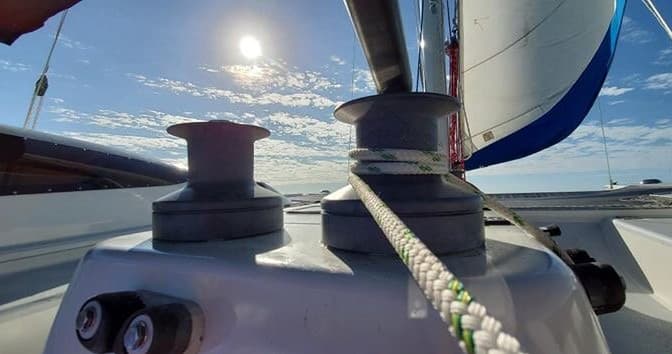 Close-up sailboat winch and rope with sunlit deck view