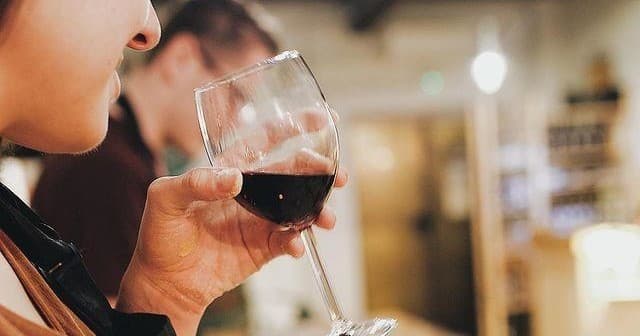 Tasting red wine indoors during a social culinary tasting event