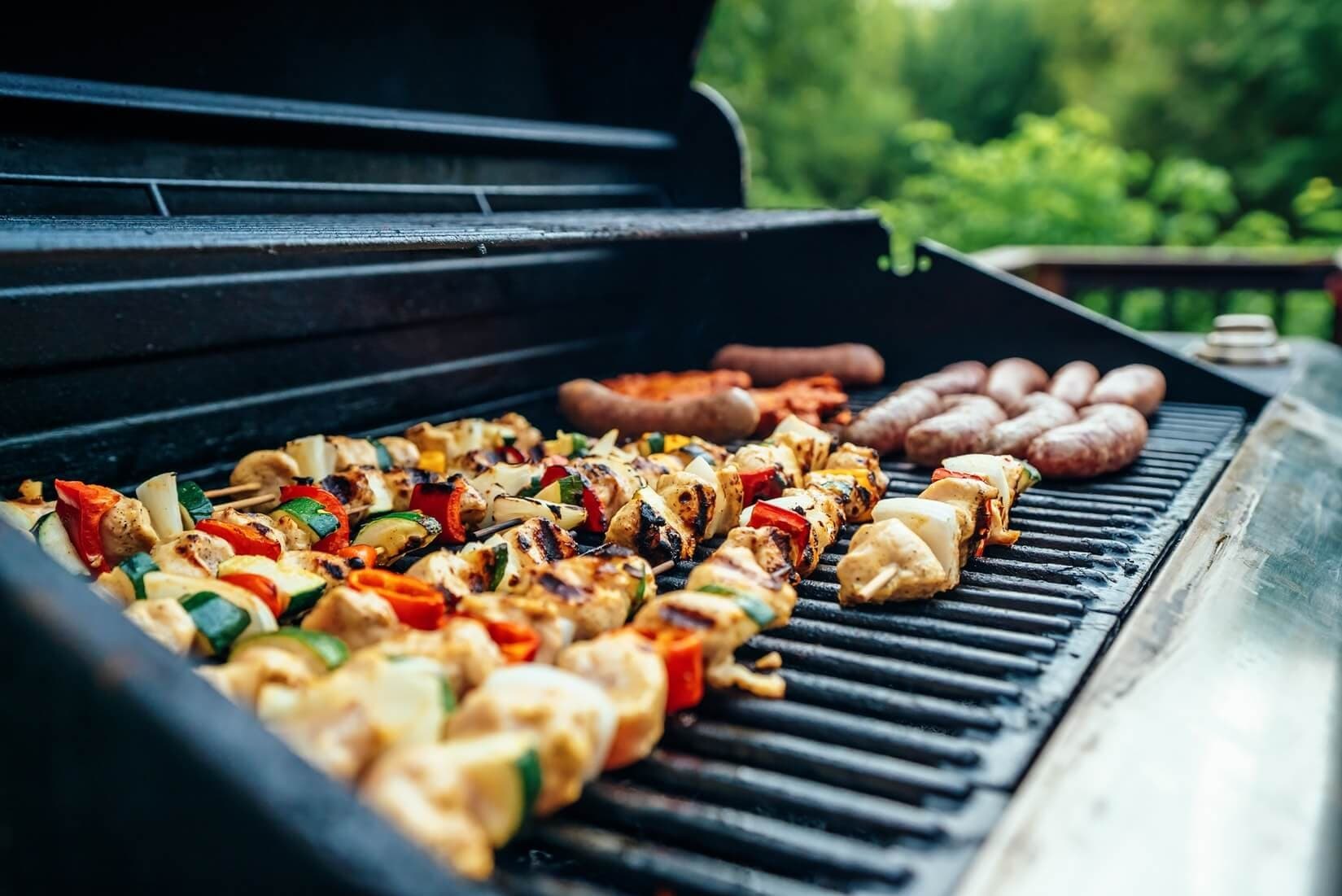 Outdoor barbecue skewers and sausages on a grill at seaside picnic