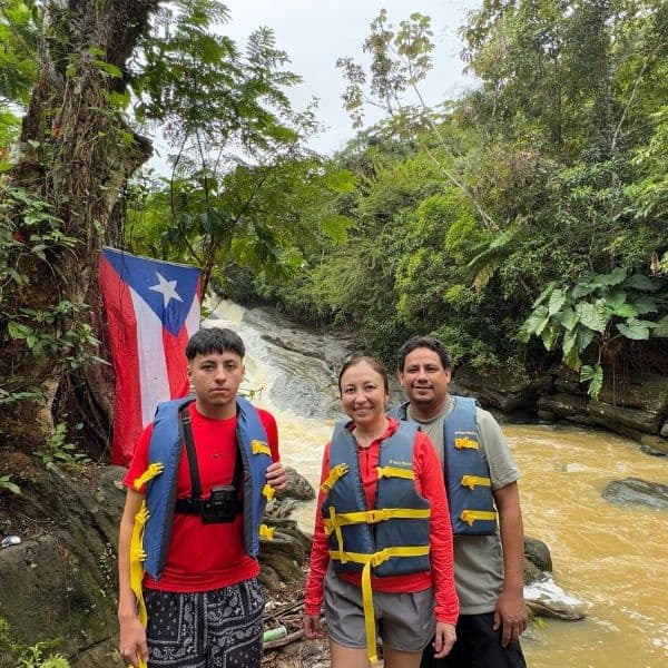 River adventure participants in life jackets beside Puerto Rico flag