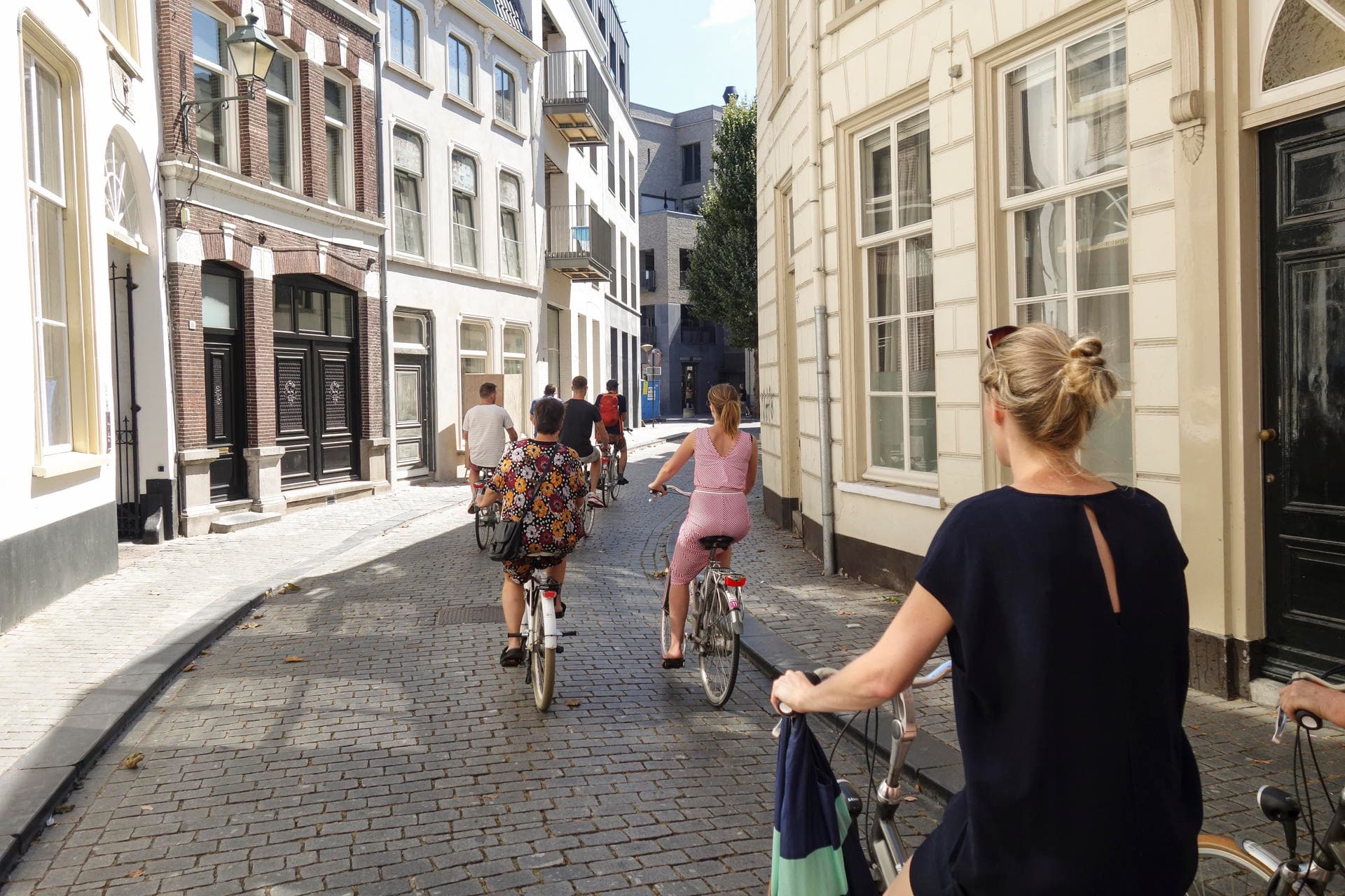 Cyclists riding historic cobblestone street in Breda tour