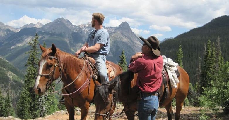 Two guides on horses overlooking rugged San Juan mountain views