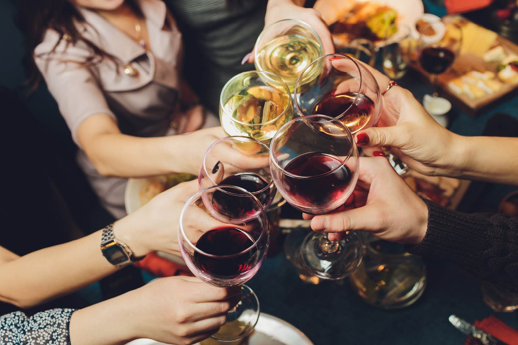 Friends clinking wine glasses over festive meal, cozy setting
