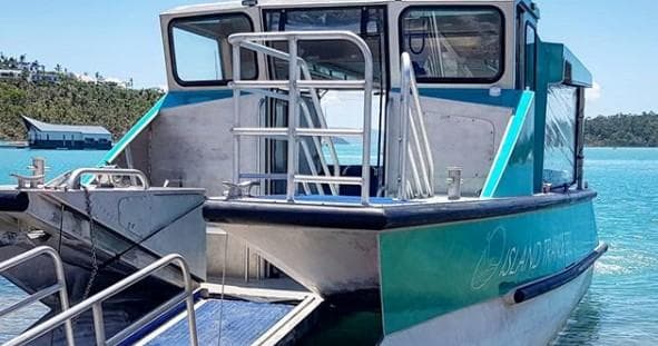 Island transfer boat docked in clear blue water for tours