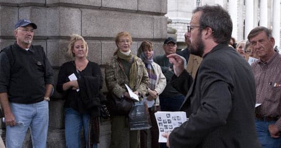 Guide leading small outdoor history walking tour along stone building