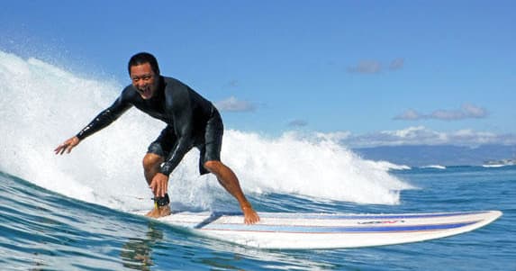 Surfer carving a wave with spray under clear blue sky