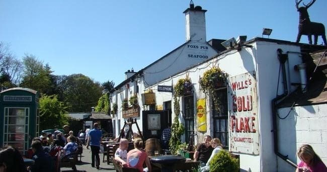 Sunny village pub courtyard with outdoor seating and crowds