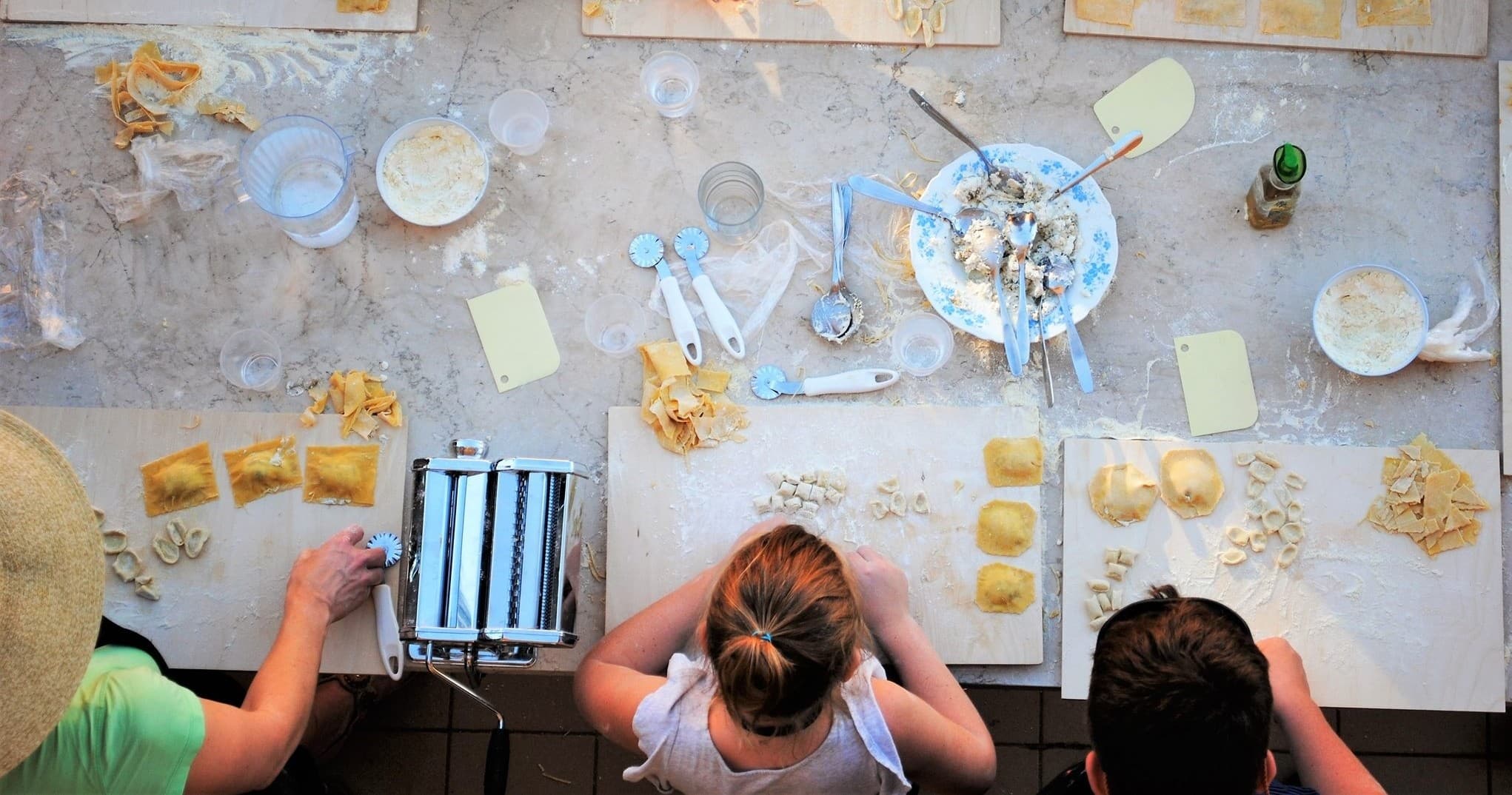 Home chefs making fresh pasta in indoor kitchen cooking class