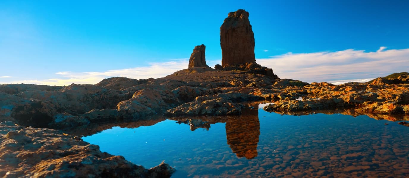 Rock formations reflected in tidal pool on rugged coastal shore