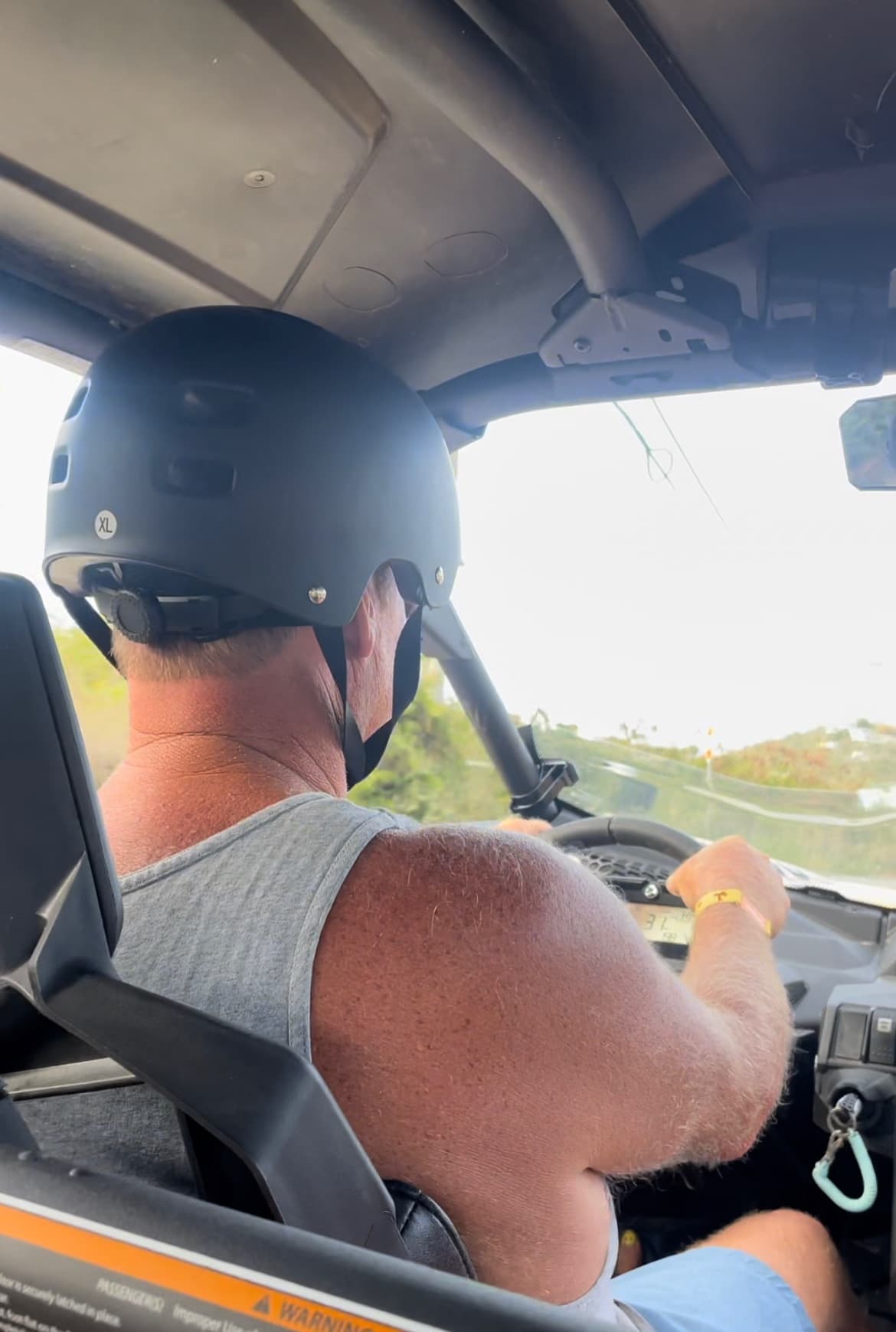Male driver wearing helmet in UTV cab navigating dirt trail ride, guided tour