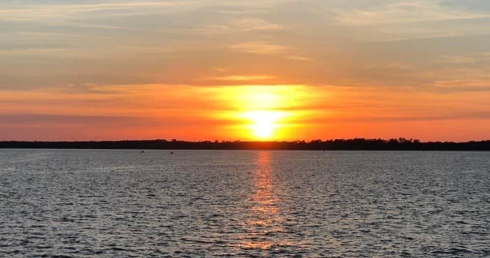 Sunset over calm bay waters with orange sky and horizon