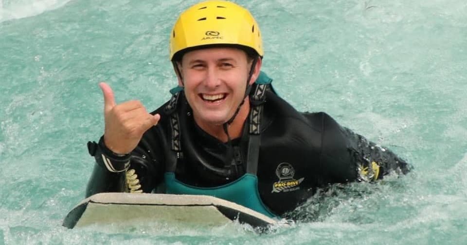 Riverboarder navigating whitewater rapids with helmet in turquoise river