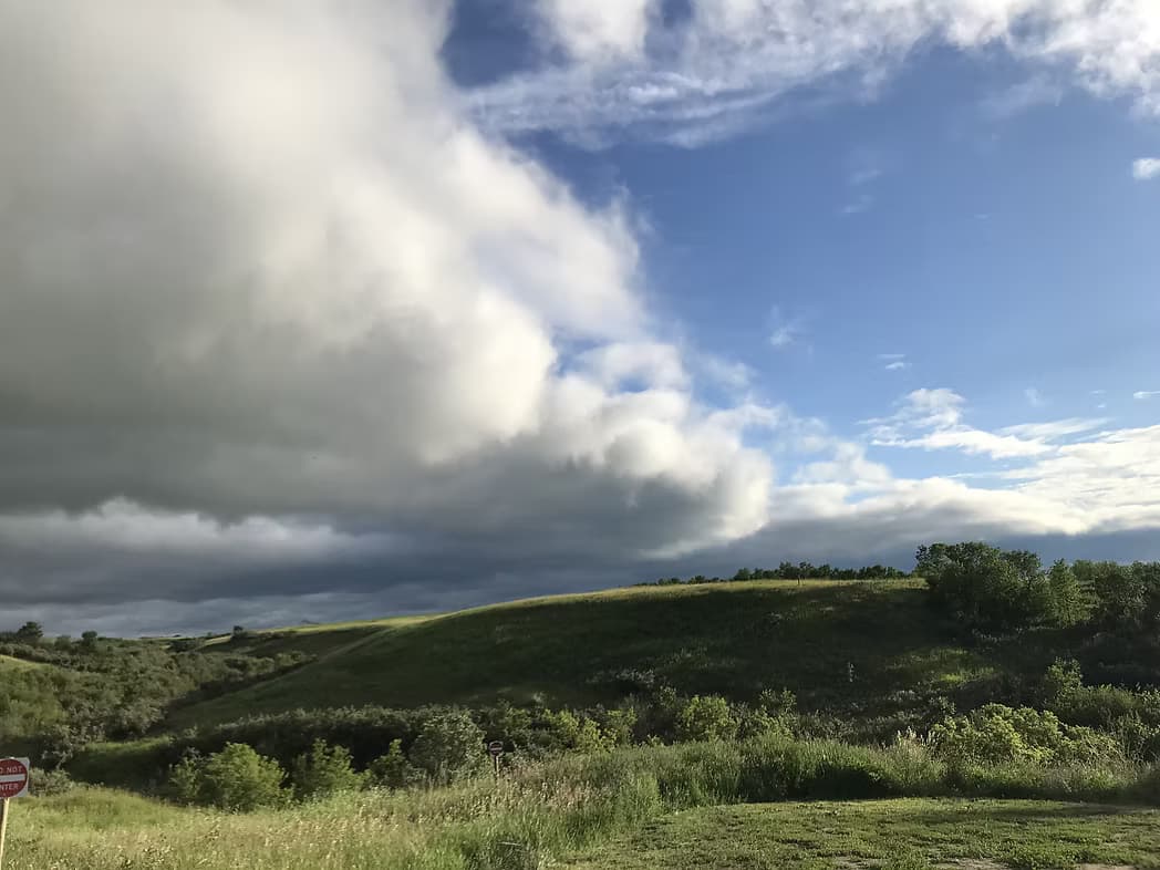 Scenic grassy hills and dramatic storm clouds at Camp Wolf Willow, hiking views