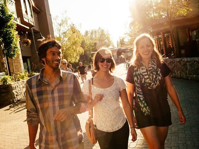 Friends walking sunny village street on Whistler tasting tour