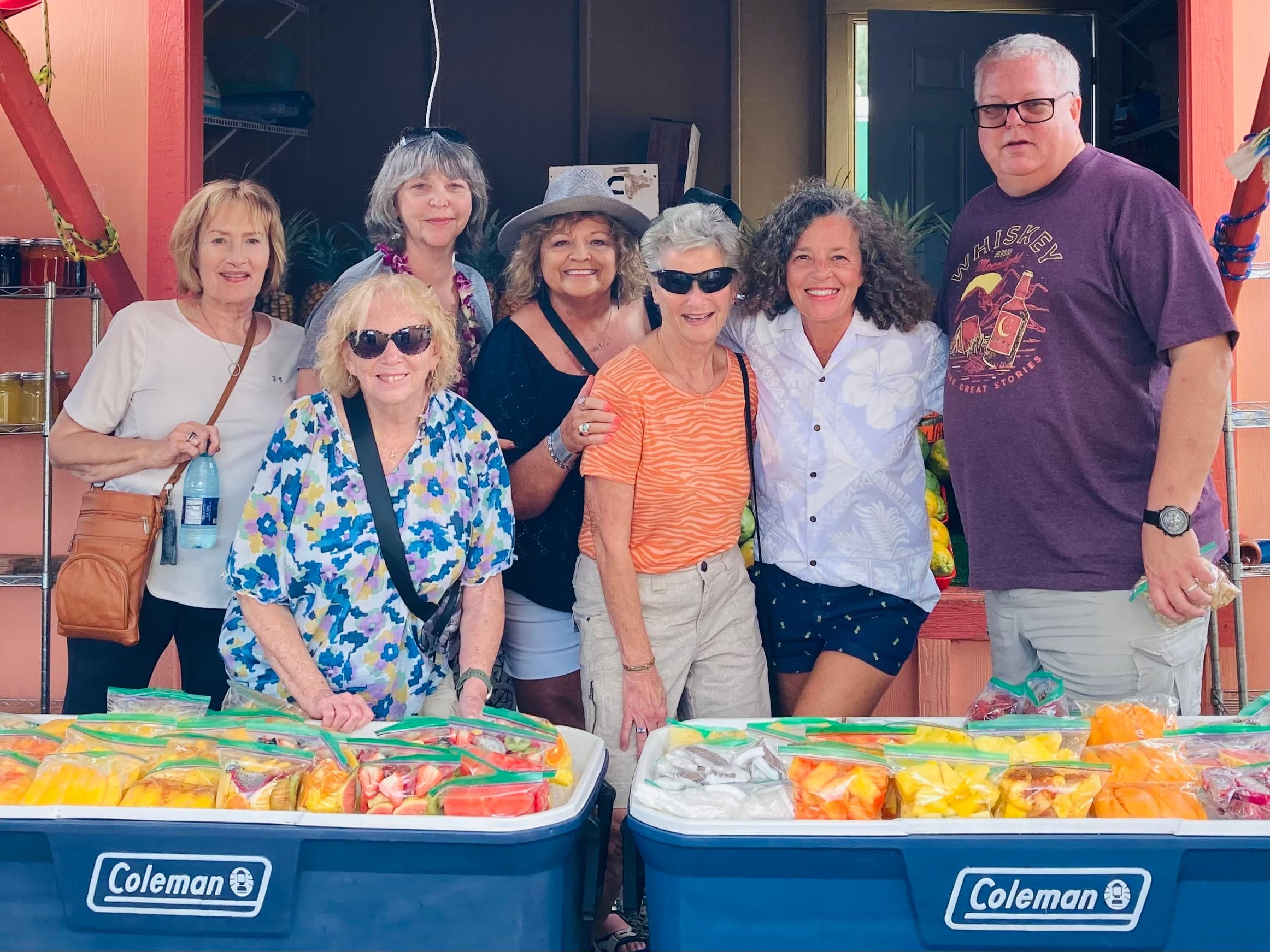 Tour group at outdoor farmers market in Oahu with coolers