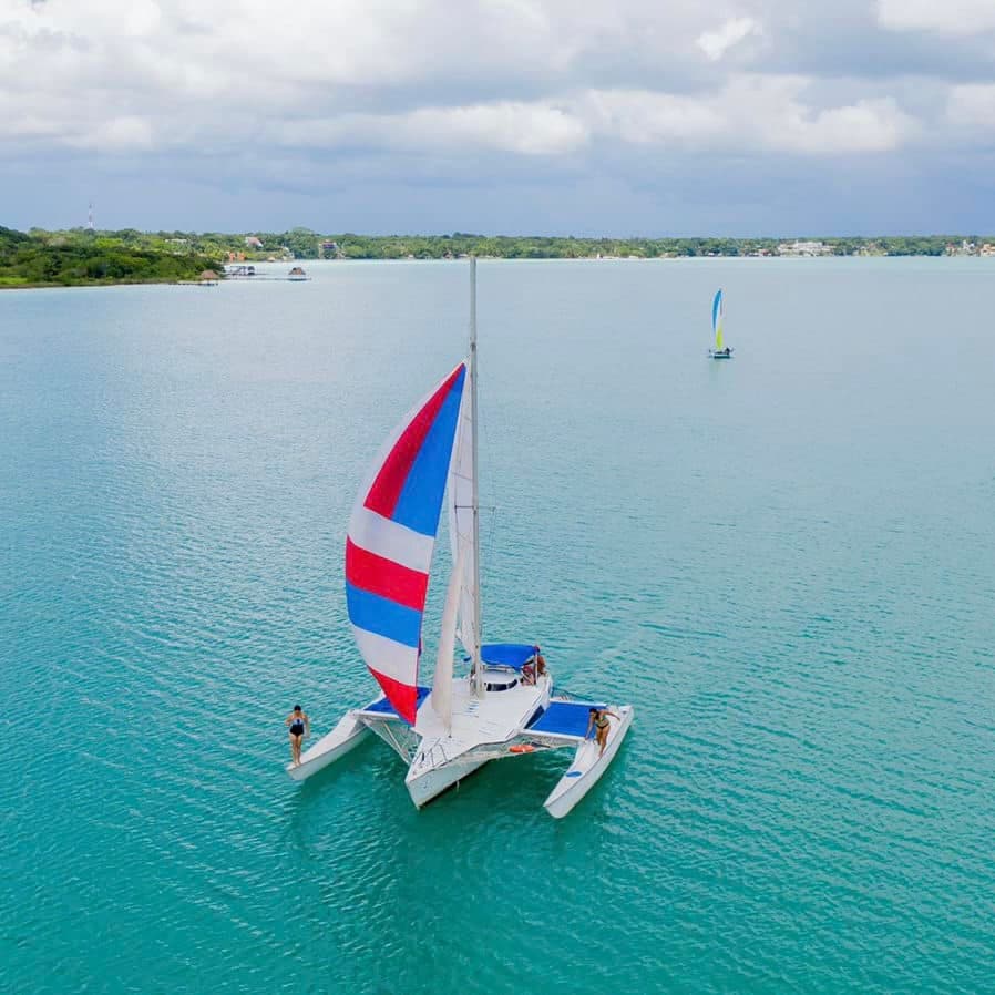 Colorful catamaran with spinnaker sailing on clear turquoise sea