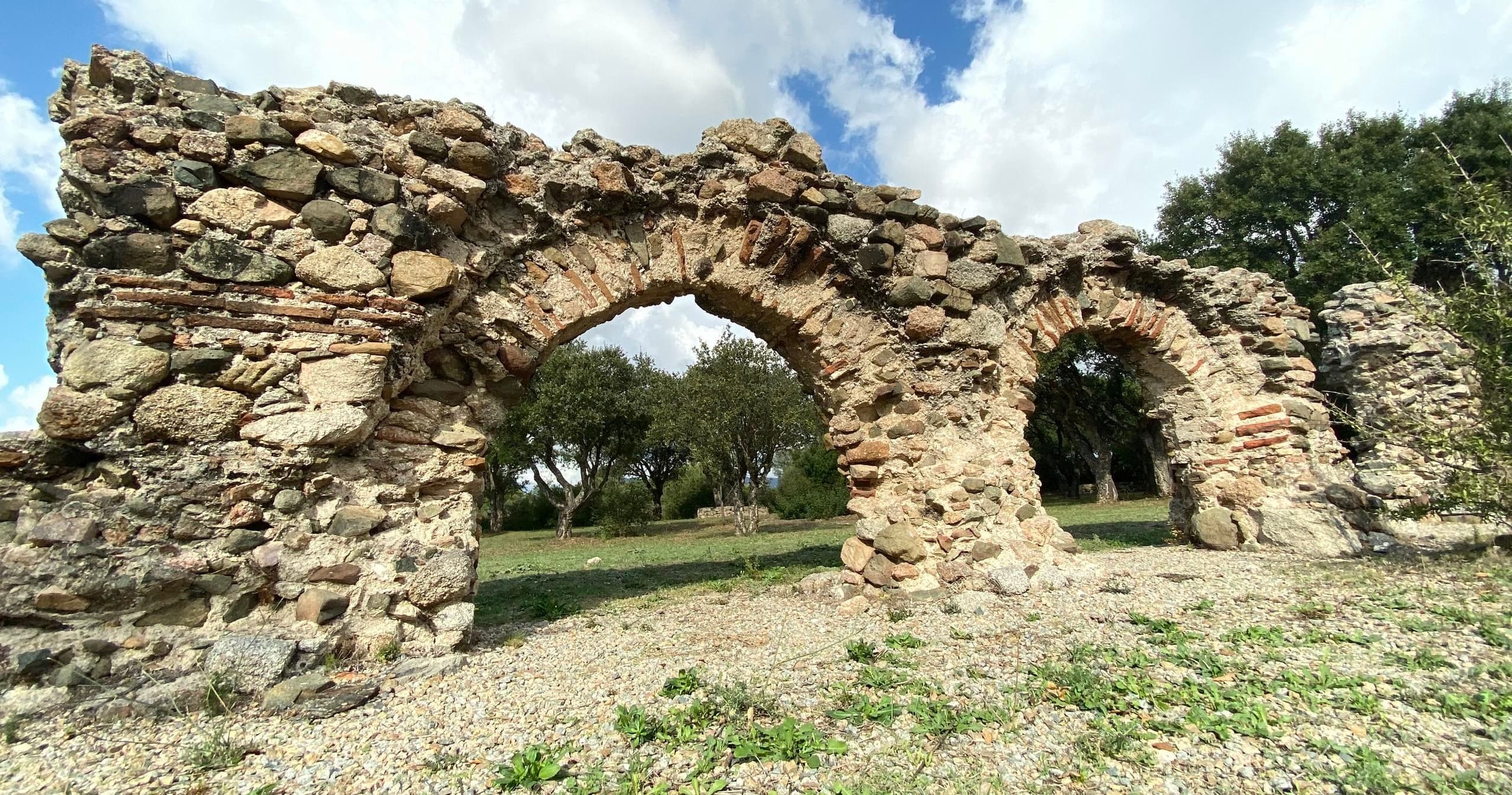 Ancient stone arch ruins in Mediterranean olive grove exploration