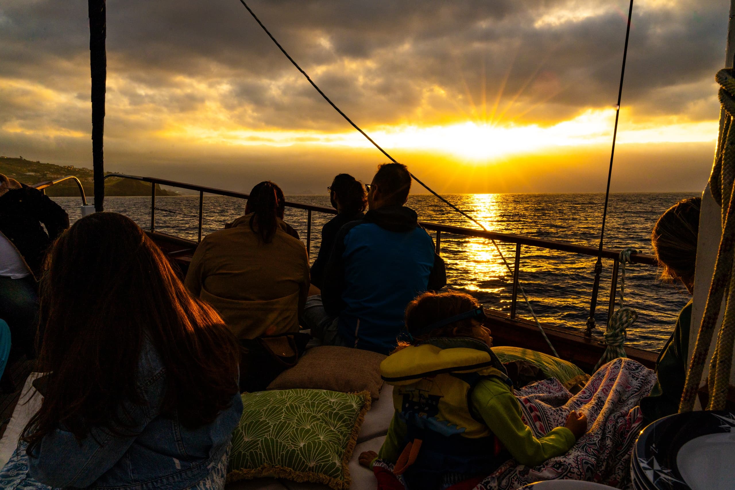 Sunset boat cruise with passengers watching golden horizon at sea