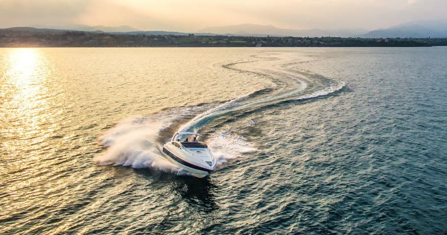 Speedboat carving wake at sunset on open coastal sea